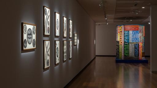 a gallery with framed black and white prints on the walls and a colorful 3D sculpture of letters in the center of the room.