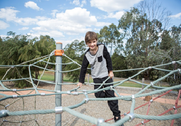 A young boy plays on a net in the park