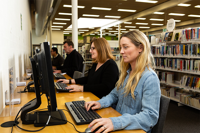 people sitting at computers in library