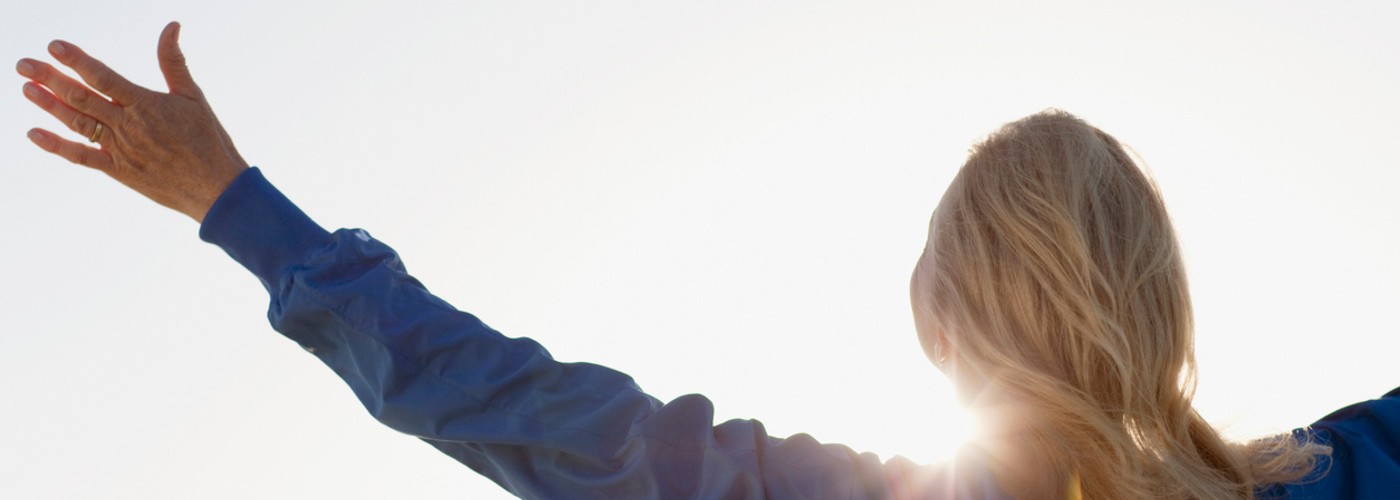 Woman with hands outstretched facing the sunshine