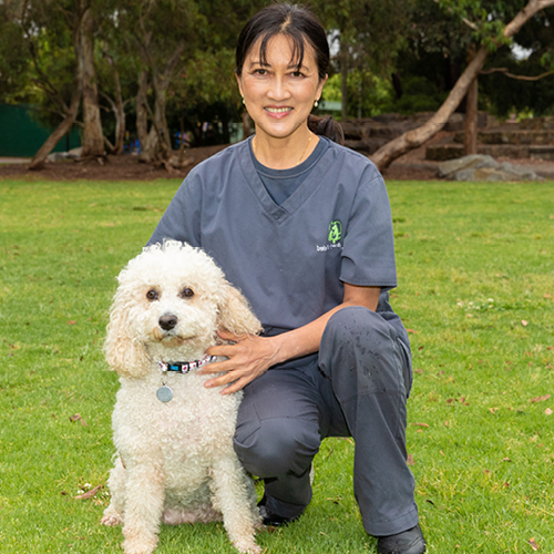 Dr Ong smiling with a white dog