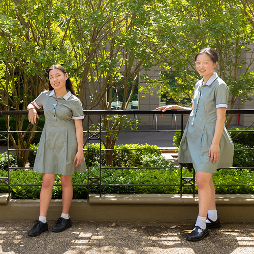 Sophie Chiew and Rino stand in their school uniforms similing at the camera