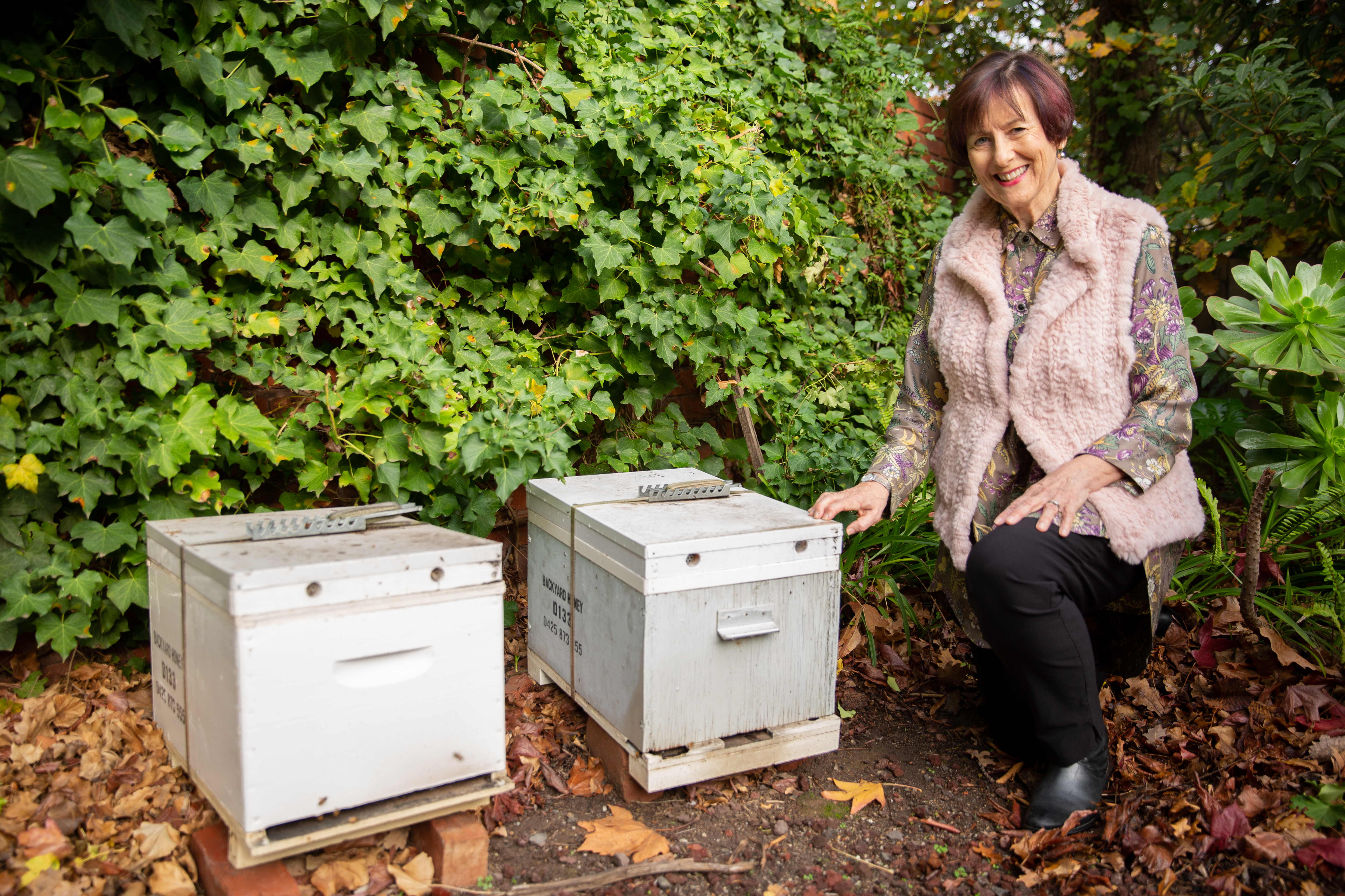 A woman next to 2 beehives