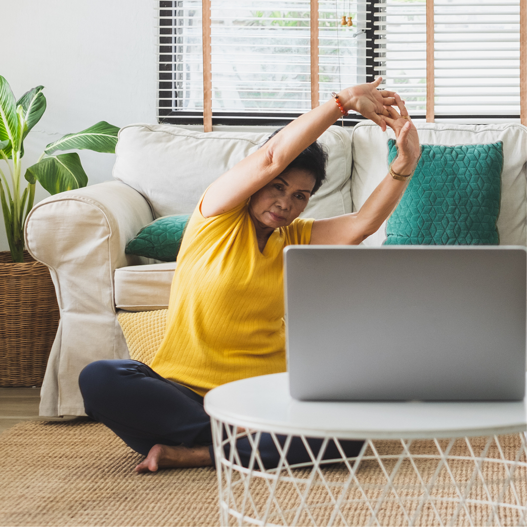 A woman stretching in front of a laptop
