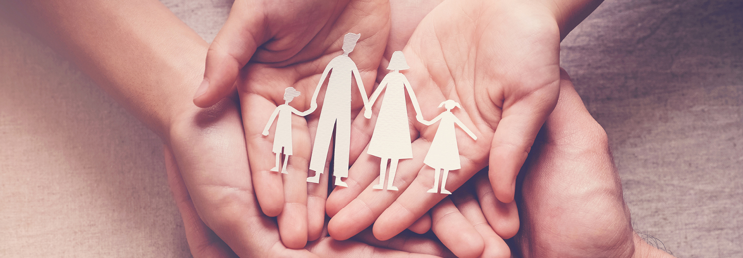 Two hands holding a paper cut-out of a family