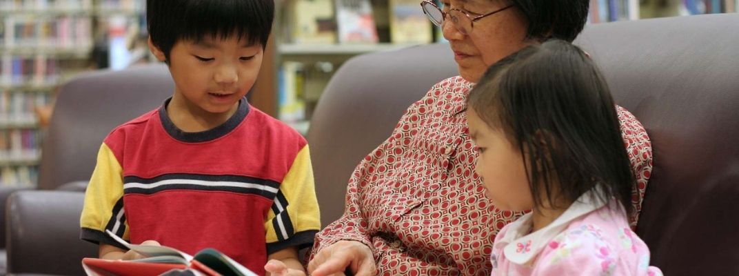Chinese grandmother reading to 2 children.