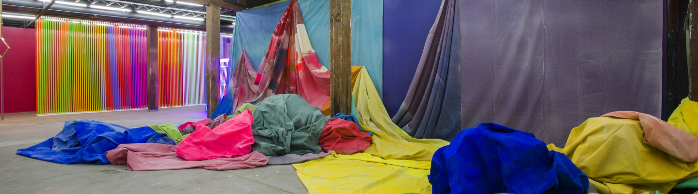 large sheets of canvas painted with bright colours and draped across the walls and piled on the ground