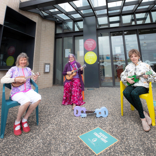 3 women sitting playing ukuleles