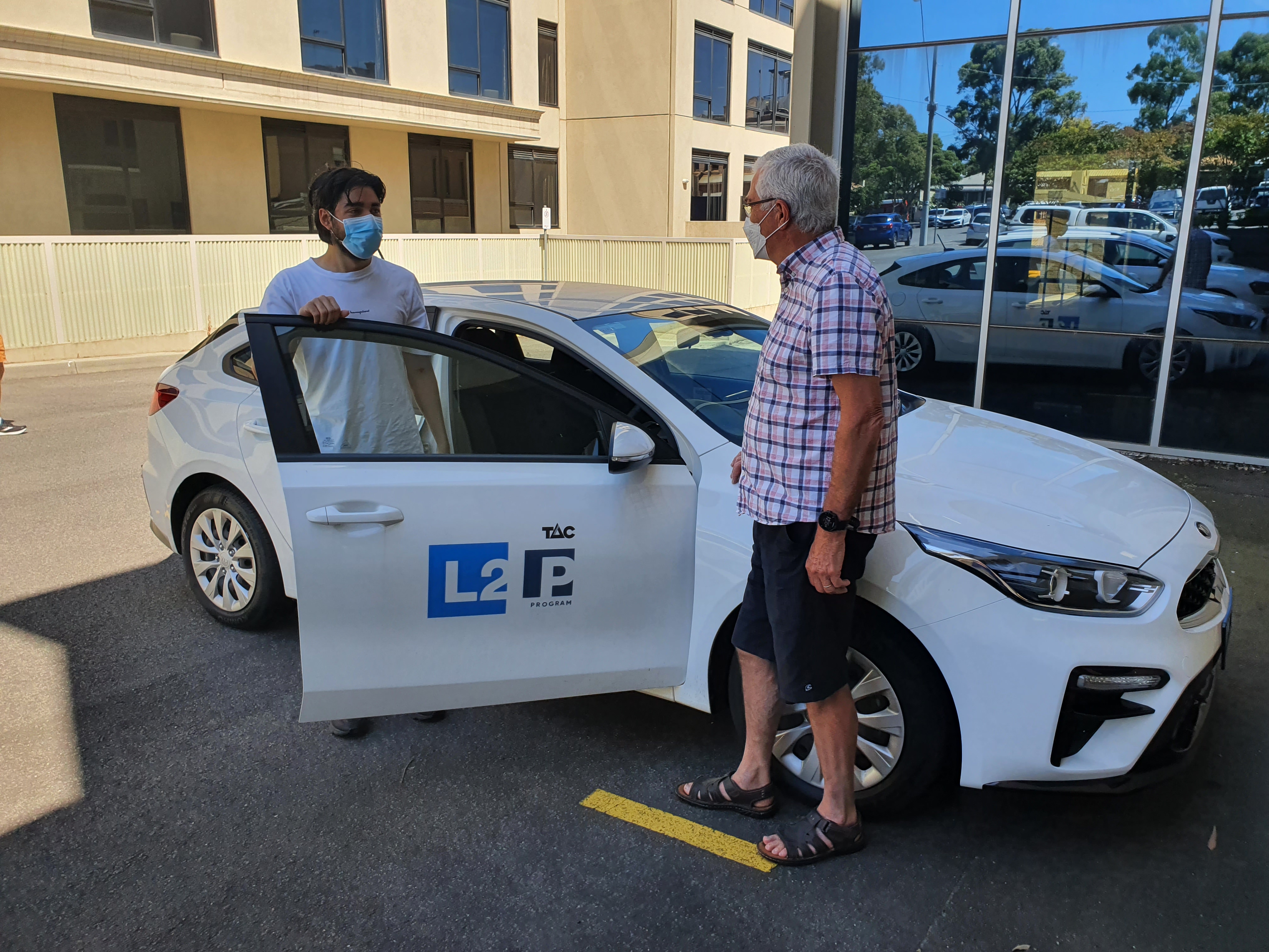 Learner driver standing with mentor near car