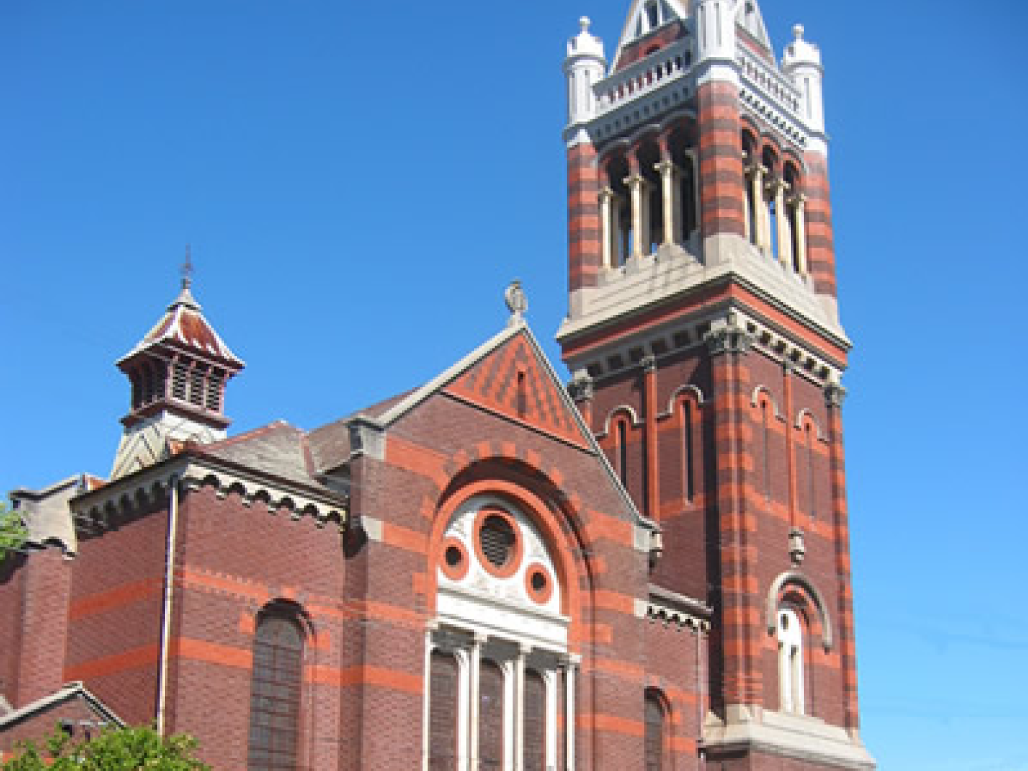 Looking up at the exterior of Auburn Uniting Church showing it's red brick design and tower