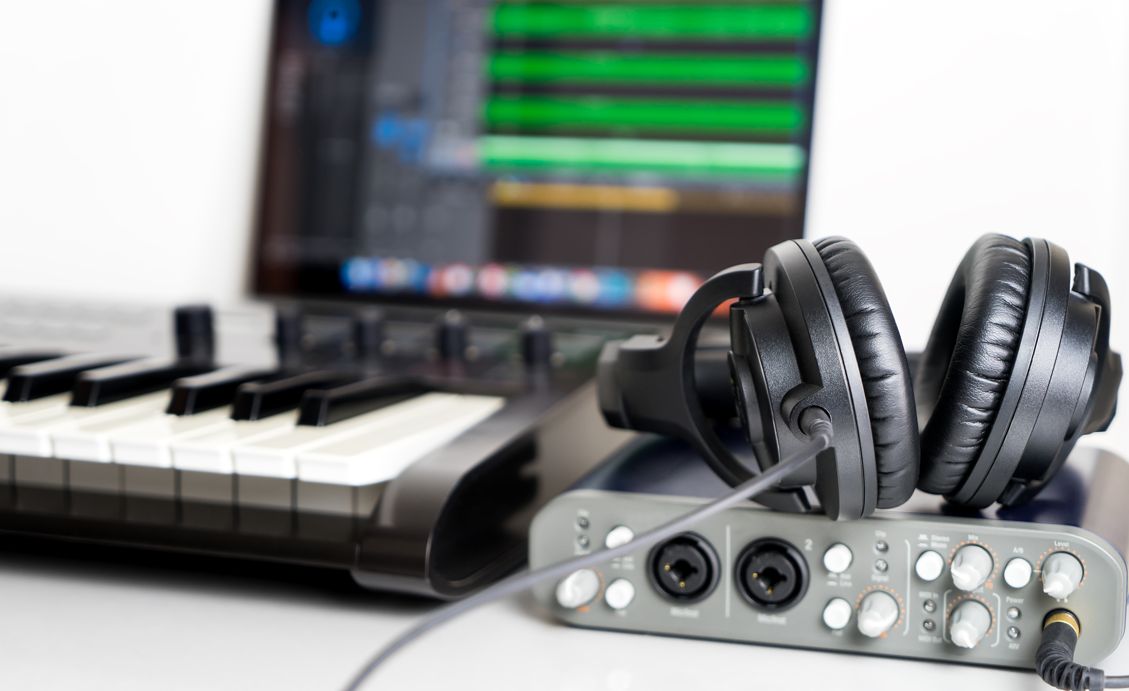 A table with a keyboard, headphones and sound mixing equipment on it