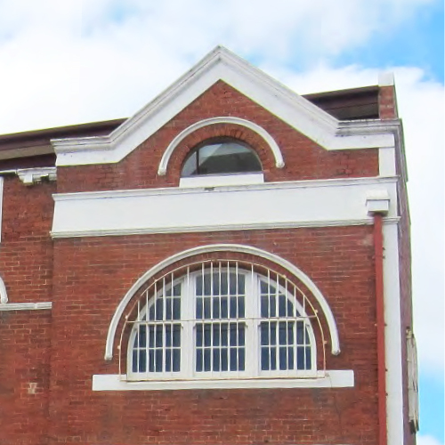 A heritage red-brick building with while accents on the windows and roofing