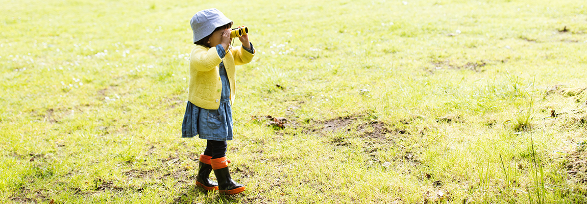 A young person looking through binoculars