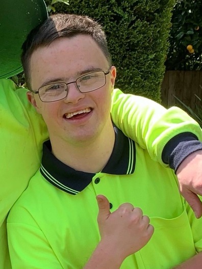 a person with downs syndrome wearing a high-vis vest and smiling