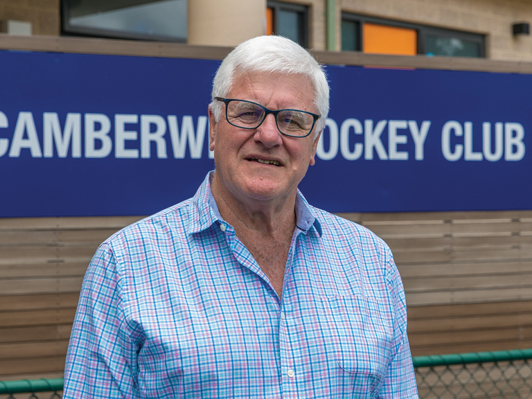 Man stands in front of a sign saying Camberwell Hockey Club