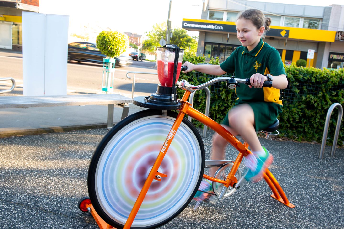 A young person riding on a stationary bike that is powering a blender making a smoothie