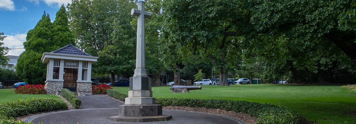 A memorial cross stands in a neatly mown park
