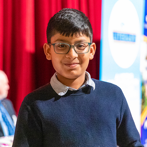 A young boy wearing glasses and a navy blue jumper