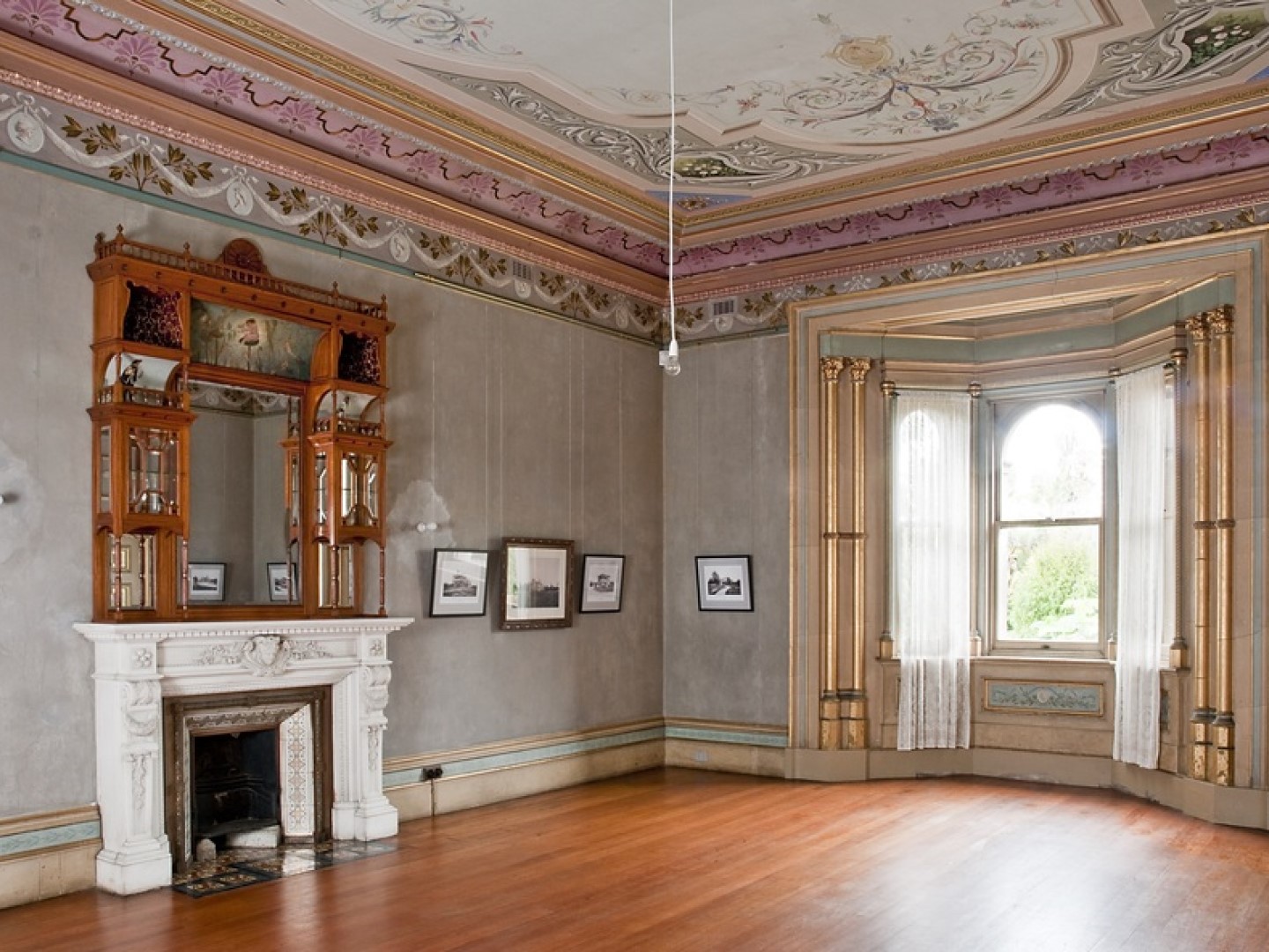 Inside the Villa Alba showing a large room with high ceilings, hardwood floors, and a fireplace and ceiling artwork that are both intricately designed and decorated