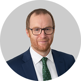 Daniel Freer wearing dark blue suit with green tie