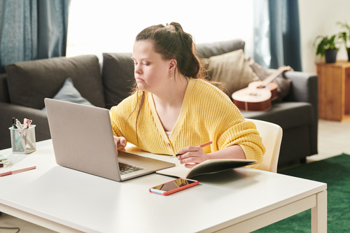 A person working on a computer and writing in a notebook