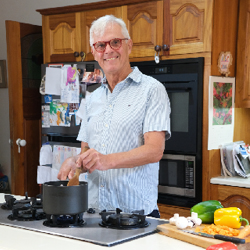 Volunteer Stephen Clarke stirs pot in home kitchen. 