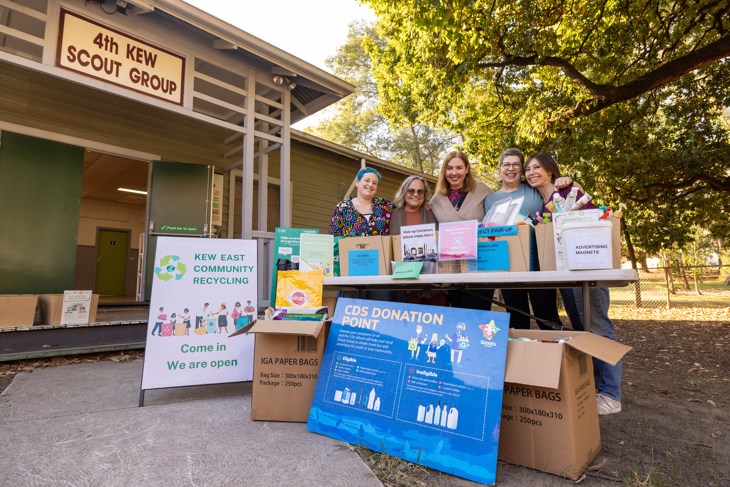 5 people standing behind a table of donated recycled items