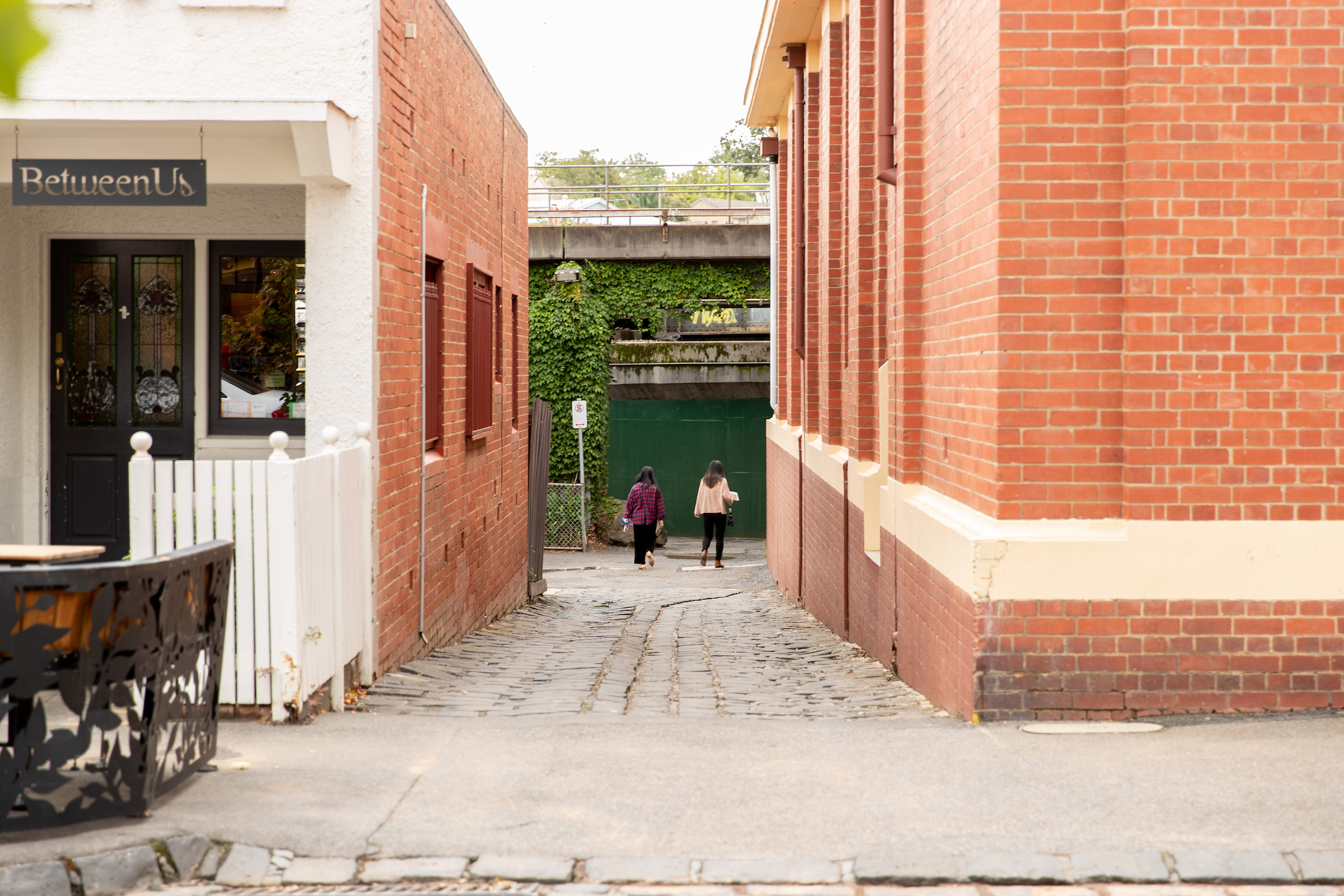 Two women walk down an aleyway.