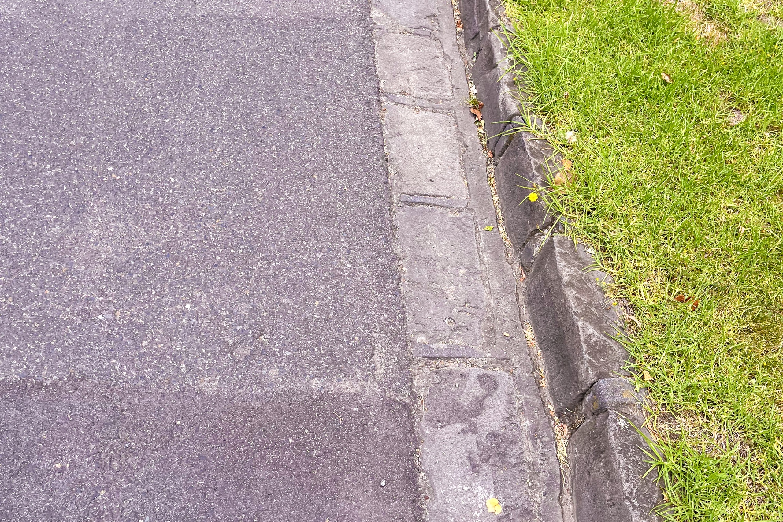 Close up shot of road, bluestone gutters and grass.
