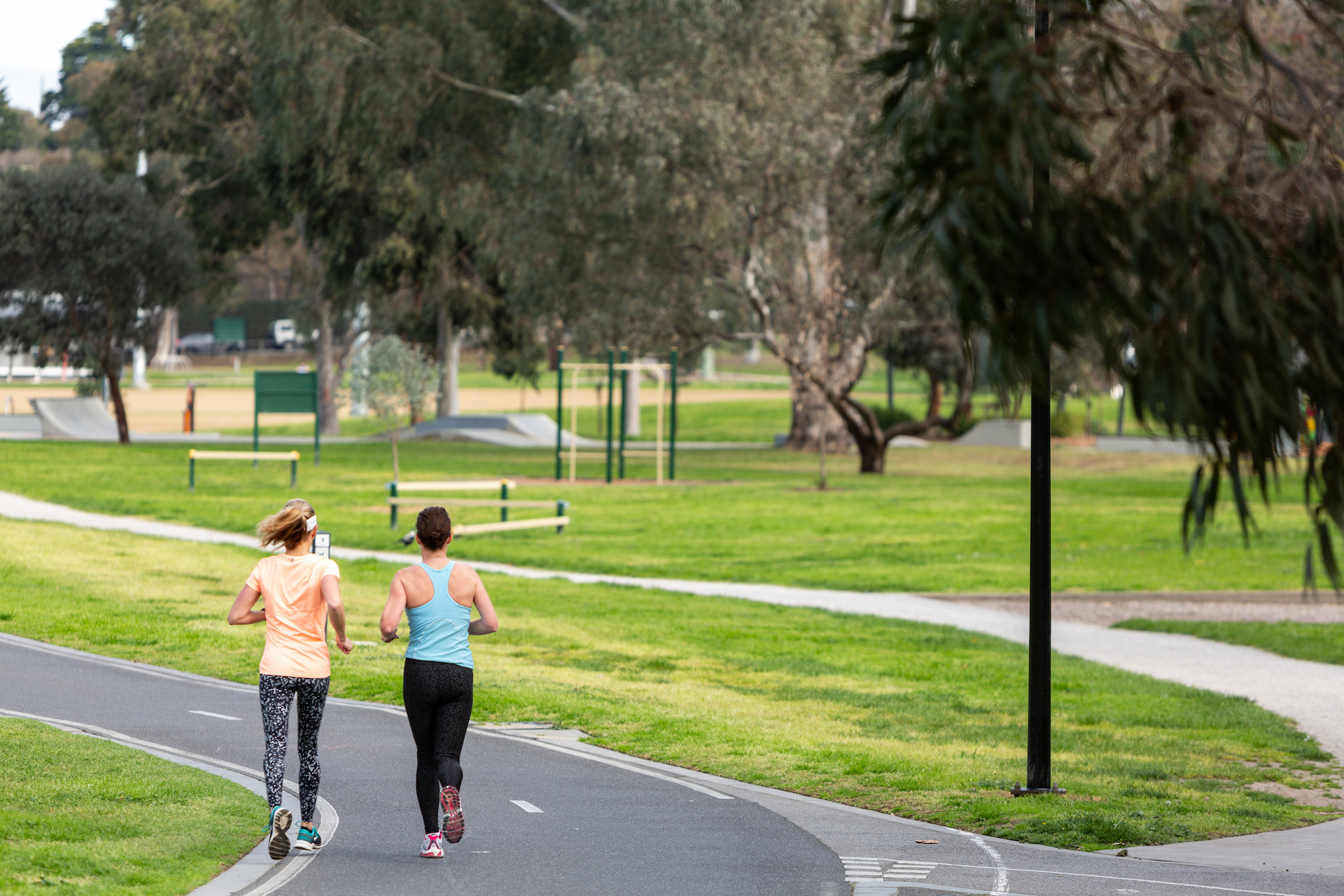Two women walk down a footpath.