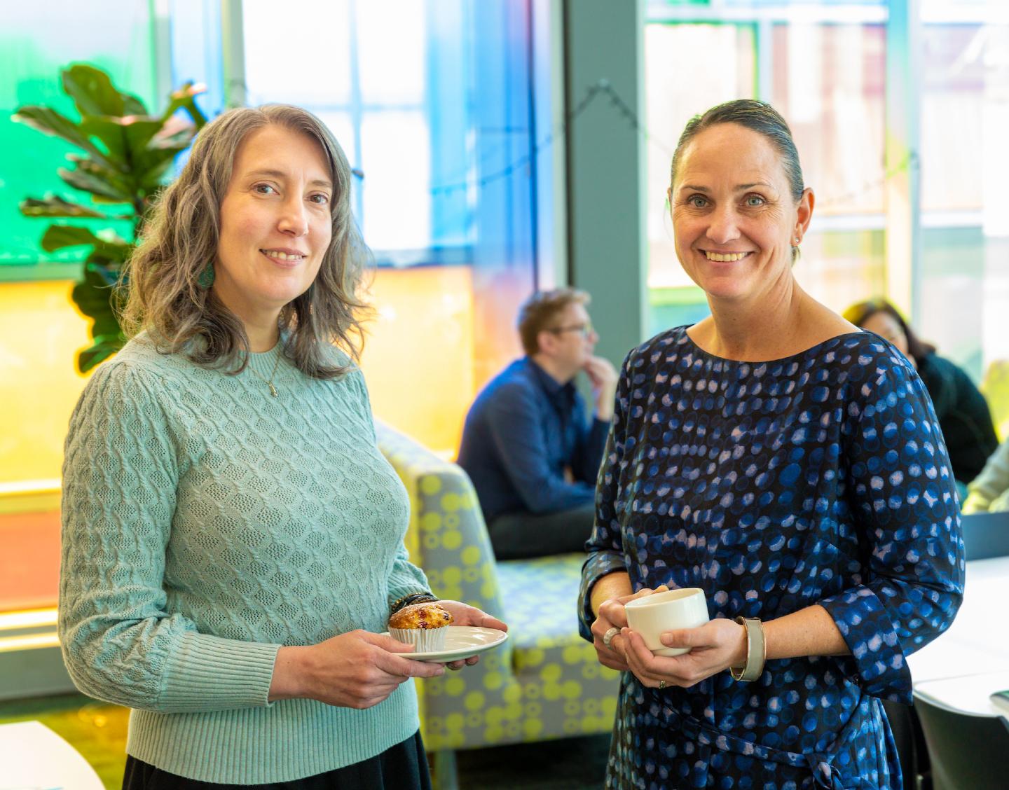 Two women standing together at a networking event holding cups