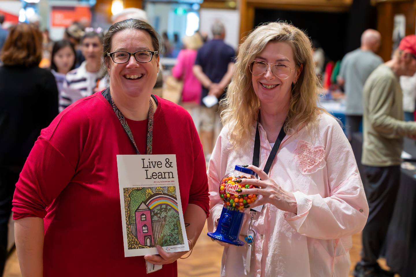 Two women standing together at an event holding a brochure for the BVRC