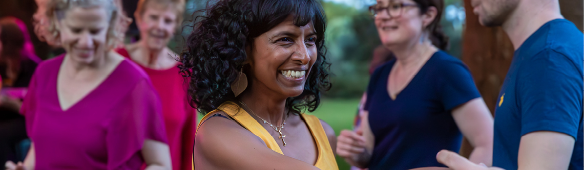 A group of people wearing different colour tops engaging in a group exercise