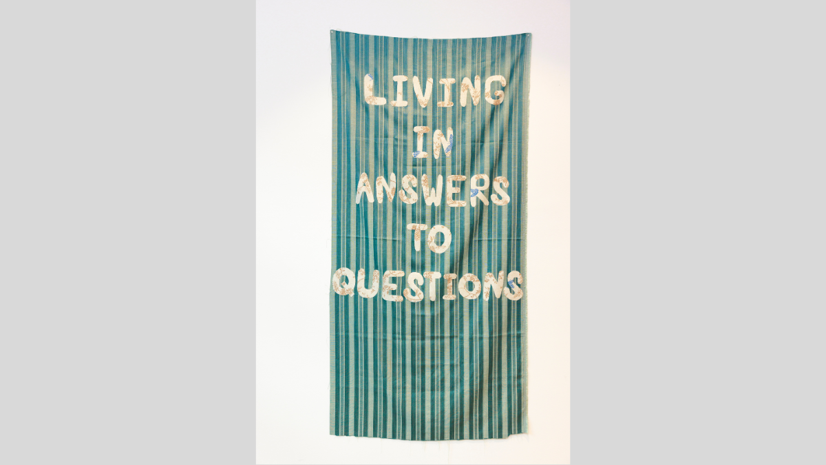 Green striped fabric banner with text that says 'Living in answers to questions'