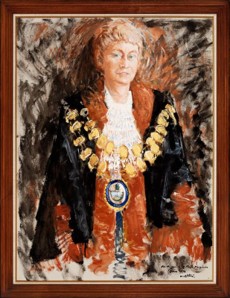 Woman with short hair standing confidently, wearing the Mayoral Robes and chain.