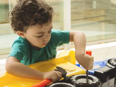 a small boy uses toy tools to fix a toy truck