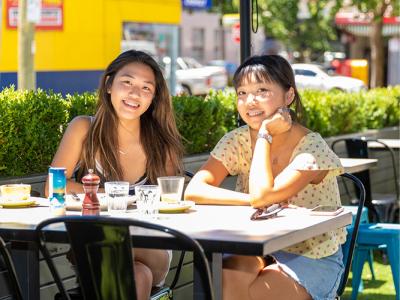 Two girls sitting outdoors at a cafe