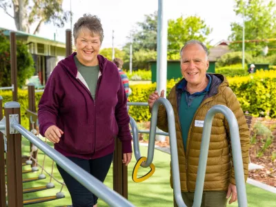 An older man and woman standing with exercise equipment