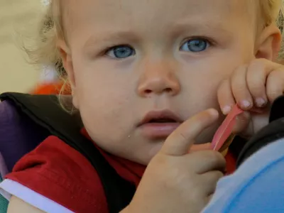 a chubby faced blond child looking thoughtful