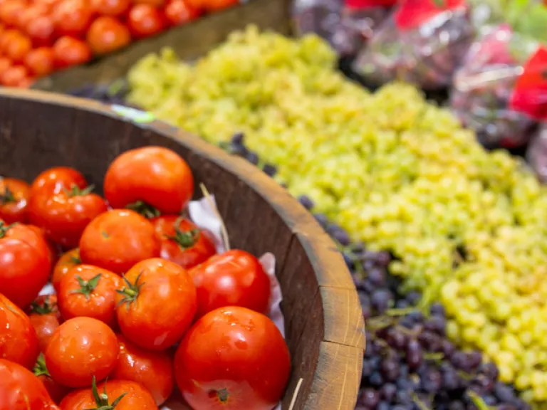 Fresh food market stall with red tomatoes and green grapes
