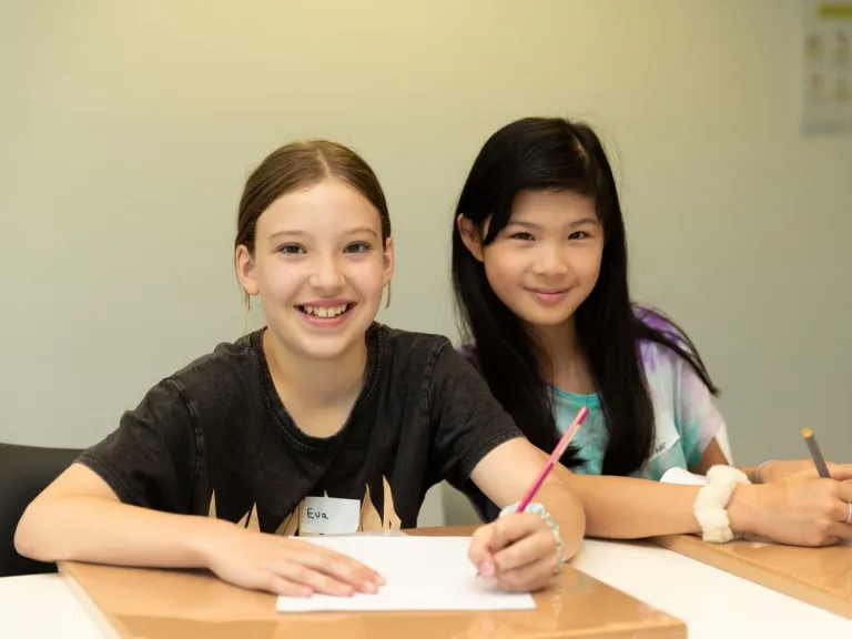 Two young people writing at a table.