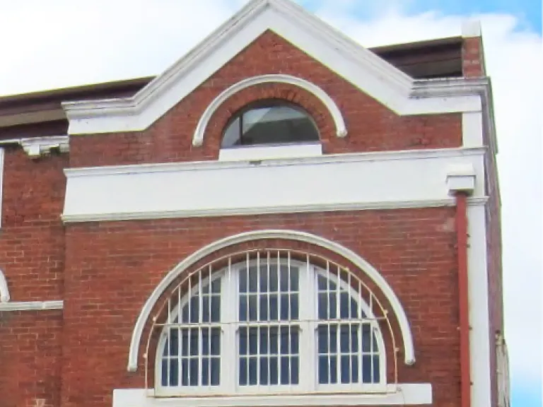 A heritage red-brick building with while accents on the windows and roofing