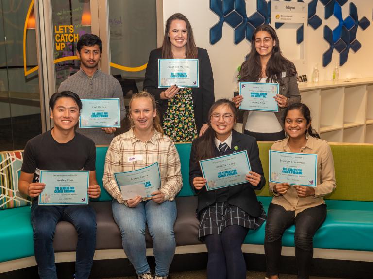 A group of young people each holding award certificates and smiling