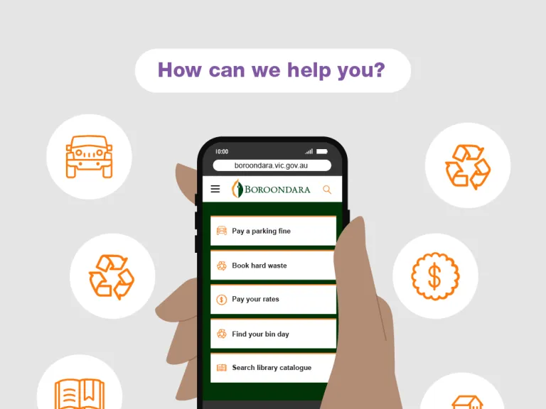 A hand holding a smart phone that shows the city of boroondara website home page, with the top task buttons showing like 'Pay a parking fine, Book hard waste, Pay your rates, Find your bin day, and Search library catalogue'
