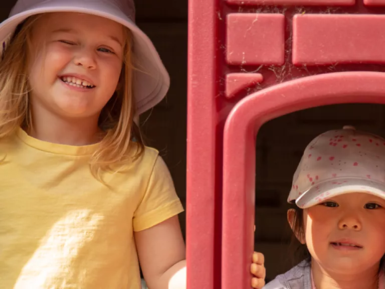 a preschool age girl winks next to a similarly aged boy in a plastic cubby