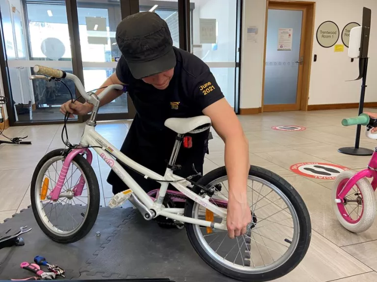 A person tightens the back wheel on a child's bike