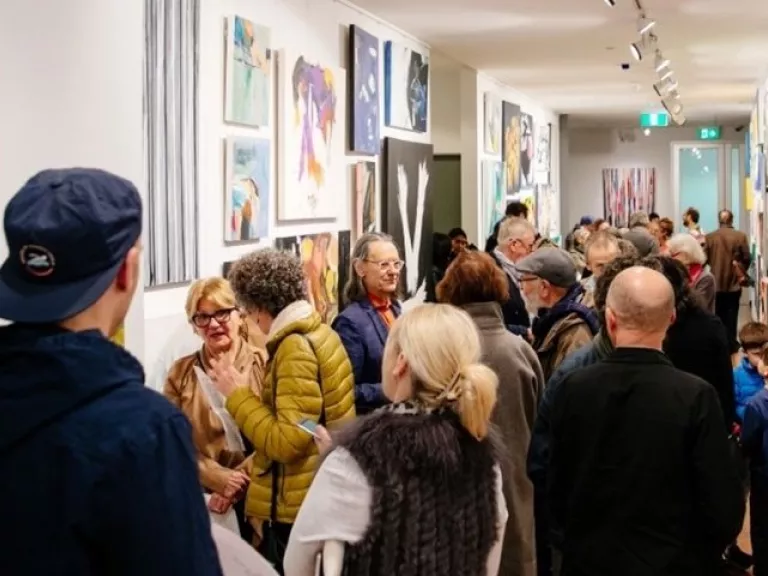 Group of people milling around artworks in a gallery