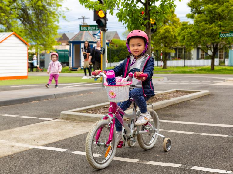 Child aged about 5 years riding a bike with training wheels at Kew Traffic School