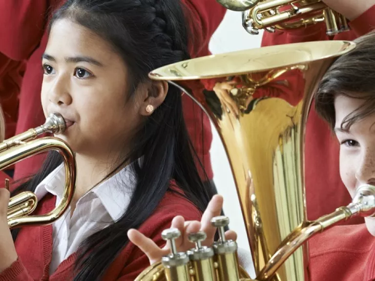 3 primary school children playing large brass instruments