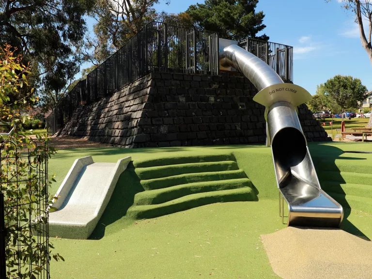 an enclosed slide and an open slide on fake grass